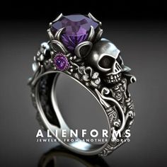 a skull ring with a purple stone in the center and skulls on it's sides