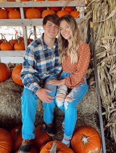 a young man and woman sitting on hay bales with pumpkins in the background