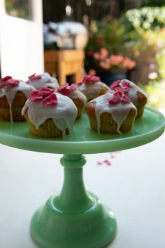 small cupcakes with white frosting and pink flowers on a green cake plate