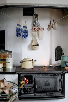 a stove top oven sitting inside of a kitchen next to a wall with hanging tea kettles