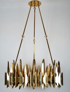 a chandelier made out of metal and gold leaf shapes hanging from the ceiling