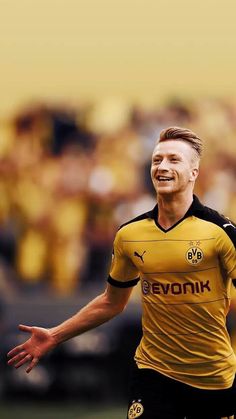 a man in a yellow soccer uniform is smiling and holding his arms out to the side