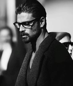 a man with glasses and a beard is looking at something while standing in front of other people