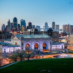 the city skyline is lit up at night, with tall buildings in the foreground