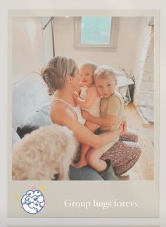 a woman holding a baby while sitting on top of a couch next to a teddy bear