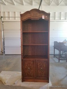 an old wooden bookcase is being repaired in a garage with the door open to reveal another piece of furniture