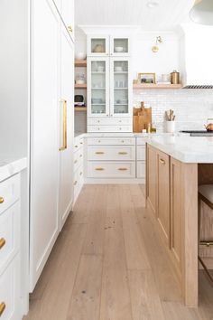 a kitchen with white cabinets and wood floors is seen in this image from the front view