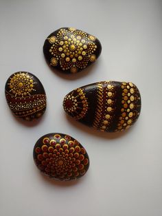 four painted rocks sitting next to each other on a white surface with circles and dots