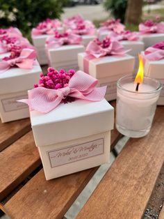 several small boxes with pink flowers on them sitting on a table next to a candle