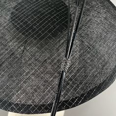 A seductive Dior style saucer in black sinamay strawcloth, with silver lurex thread. Simply and strikingly trimmed with two arrow feathers and one ostrich quill in black. Elastic and comb attachment for easy, comfortable wear. Lifted Millinery headwear is constructed with time honored techniques and fine craftsmanship. All hats are meticulously blocked and sewn by hand without the use of adhesives to attach trims. This ensures a long lasting hat with the ability to be retrimmed throughout the ye Dior Style, Arrow Feather, Hat Box, Comb, Hand Sewing, Feathers, Dior, Thread, Long Lasting