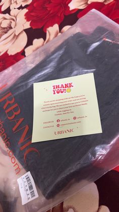 a thank you card in a plastic bag on a floral print tablecloth with the words thank you written on it