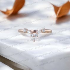 a diamond ring sitting on top of a white tablecloth with leaves in the background