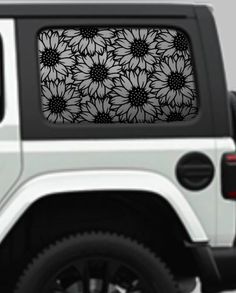 a white jeep with sunflowers on it's side and the window sticker is