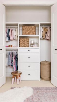 a white closet with clothes and baskets on the shelves