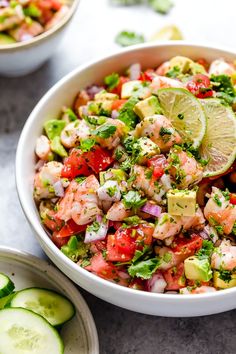 a bowl filled with salad next to cucumbers and limes on the side