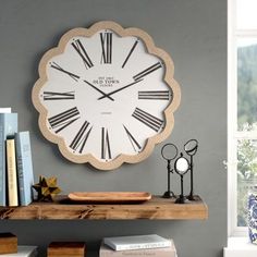 a large clock mounted to the side of a wall next to a book shelf filled with books