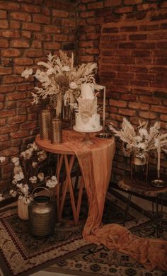 a table with flowers and candles on it in front of a brick wall