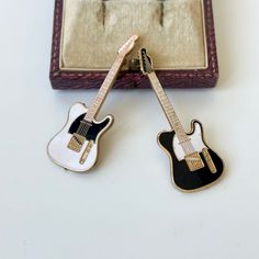 two miniature guitars sitting on top of a table next to a case with a guitar in it