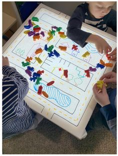 two children are playing with their hands on a board that is made out of construction paper