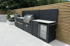 an outdoor bbq and grill area with wood slats on the wall behind it