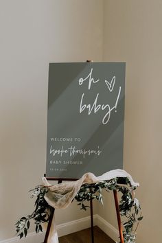 a welcome sign for a baby is displayed on an easel in the corner of a room