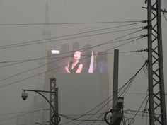 a large billboard with a woman on it in the middle of power lines and buildings