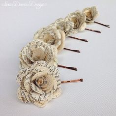 three old book page roses are sitting on a white tablecloth with wooden sticks in the middle