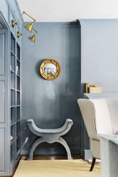 a living room with blue walls and a gold clock on the wall above a bench