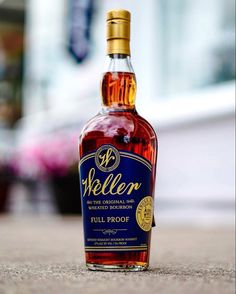 a bottle of weller full proof whiskey sitting on the ground in front of a building