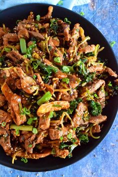 a bowl filled with meat and broccoli on top of a blue table cloth