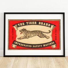 the tiger brand framed in black frame on wooden floor next to wall with white walls