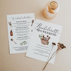 the wedding stationery is laid out next to some flowers and a vase with an acorn on it