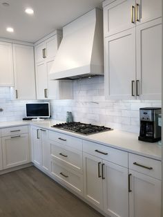 a kitchen with white cupboards and an oven in the center is shown, along with a computer on the counter