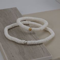 "The perfect accessories on or off the beach!  Natural white heishi shell beads are simply beautiful in their simplicity.  Also known as African disc beads, these genuine seashells offer a cool symmetry, yet each bead is unique. SIZE Each Heishi disc bead measures approximately 6mm. We'll hand string these beautiful beads as a bracelet or anklet - select your perfect size in the dropdown box. MATERIALS Genuine Heishi shell beads  -- bracelet or anklet -- Hand strung on strong stretch cord. Your White Strand Stretch Bracelet For The Beach, White Stackable Beaded Bracelets For Beach, White Stackable Bracelets For Beach, Minimalist White Beaded Bracelets For Beach, White Minimalist Beaded Bracelets For Summer, Adjustable White Stretch Bracelet For Summer, Minimalist White Beaded Bracelets For Summer, Flexible White Bracelets For Summer, Seashell Anklet