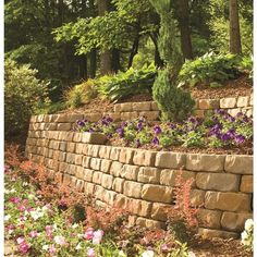 a stone wall surrounded by flowers and trees