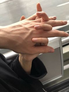 two hands reaching out to each other on a subway train window ledge, with one hand holding another's arm