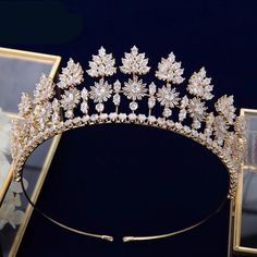 a gold tiara with white flowers and leaves on it, next to two framed pictures