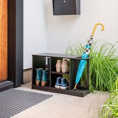 an umbrella and several pairs of shoes are sitting on the ground in front of a door