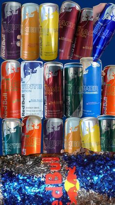 several cans of various types of beverages are stacked on top of each other in front of blue tinsel