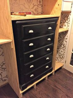 an old dresser is painted black and has silver knobs