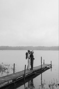 three people standing on a dock in the water