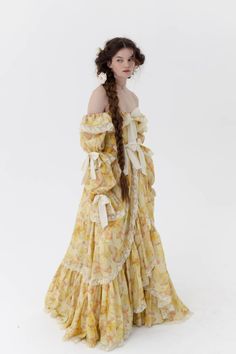 Evoking the effervescent glow of sunshine and the fairyesque charm of butterflies, this gown embodies the essence of joy and light. Its butterfly-printed fabric in cheerful yellow hues, matched with layers of voluminous organdy, captures the spirited delight of girlhood while the long sleeves, adorned with ties and lace trim, mirror the cinched details of the skirt. The off-the-shoulder neckline strikes a perfect balance, accentuated by charming bows at the bust, waistline, and sleeves. You won’ Silk Dressing Gown, Yellow Hues, Corset Skirt, Puff Dress, Floor Length Gown, Knitted Coat, Waltz, The Sunshine, Printed Fabric