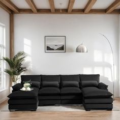 a living room with a large black couch and wooden beams on the ceiling, along with a white rug