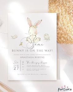 a bunny is on the way baby shower card with straw hat next to it and flowers