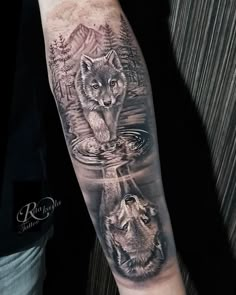 a man's arm with two wolfs in the water and trees on it