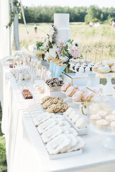 a table filled with lots of desserts on top of a white table cloth covered table