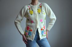 Vintage 60s / 70s cream (with yellow undertone) acrylic cardigan with floral embroidery in pink, yellow, green orange and blue Material - 100% Acrylic ( feels very synthetic) Made in Korea Size on tag - marked M, but runs small. Shown on size 38 EU/ 8 US, fits small. Will fit better as S or small M (36 EU) Measurements (taken while garment is lying flat, duble armpit to armpit): Shoulders - Undefined Armpit to Armpit (double that): 19 inches / 48.3 cm Sleeve Length, measured from neckline: 22 in Cream Floral Embroidery Cardigan For Spring, Cream Floral Embroidered Cardigan For Spring, Vintage Floral Print Spring Cardigan, Vintage Cream Sweater With Floral Embroidery, Vintage Floral Embroidered Sweater For Spring, White Vintage Cardigan With Floral Embroidery, Cream Sweater With Floral Embroidery For Spring, Cream Floral Embroidered Sweater For Spring, Vintage Embroidered Sweater For Spring