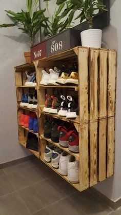 a wooden shoe rack with many pairs of shoes on it and a potted plant in the corner