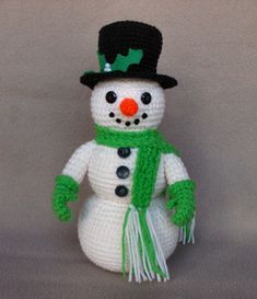 a crocheted snowman with a green scarf and hat on it's head