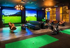 an indoor golf simulator with green carpet and chairs